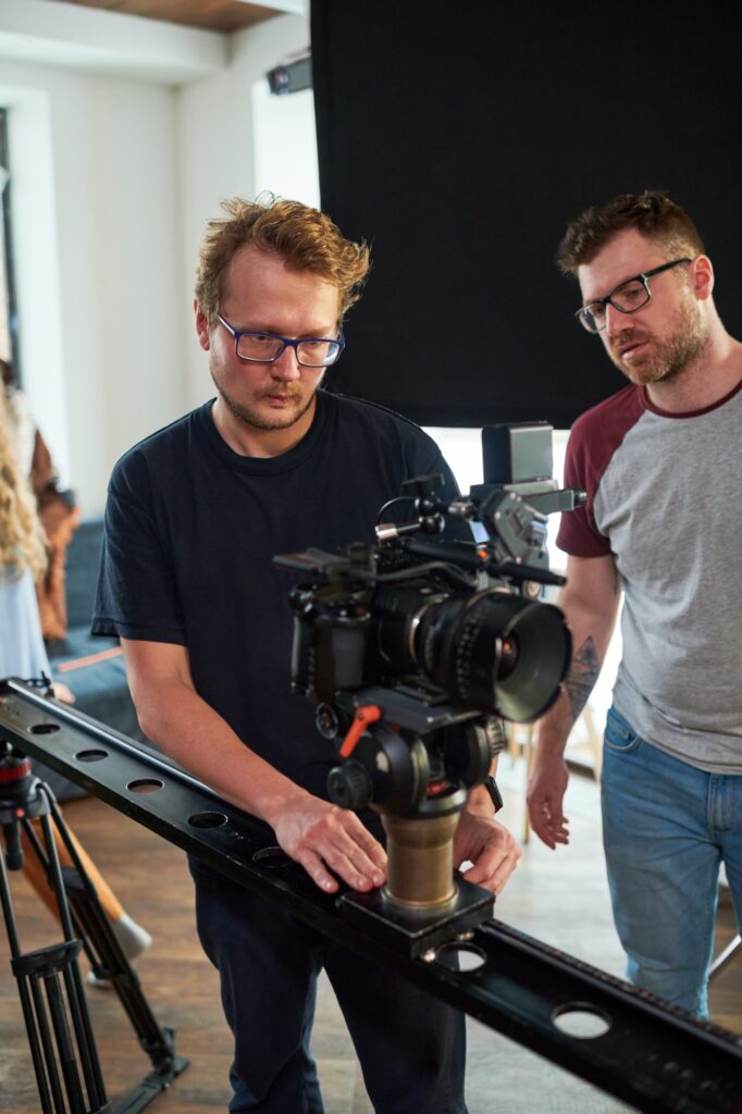 Young professional videographer moving video camera along slider